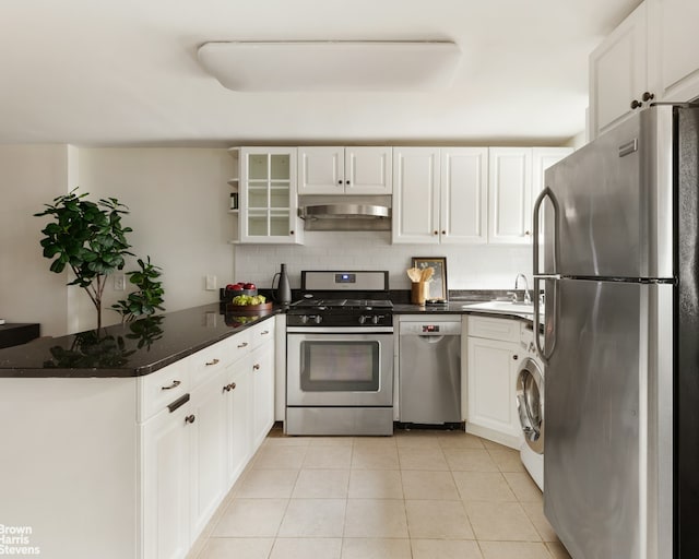 kitchen featuring under cabinet range hood, decorative backsplash, washer / dryer, a peninsula, and stainless steel appliances