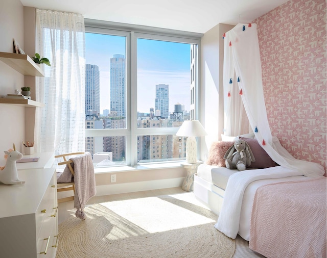 bedroom featuring a view of skyline, wallpapered walls, and multiple windows