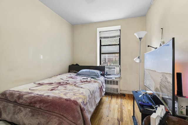 bedroom with light wood-type flooring, cooling unit, and radiator heating unit