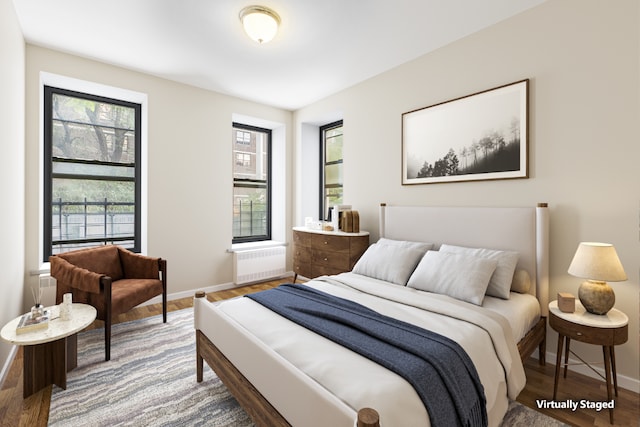 bedroom with radiator, baseboards, and wood finished floors