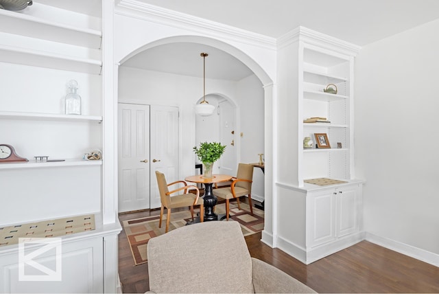 dining area featuring dark wood-type flooring, built in shelves, baseboards, and arched walkways