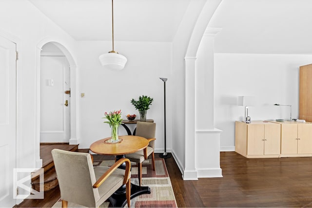 dining space with baseboards, arched walkways, and dark wood-type flooring