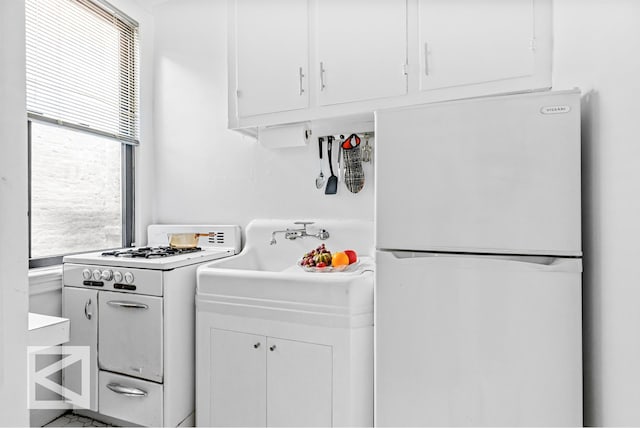 kitchen featuring light countertops, a sink, white cabinets, and white appliances