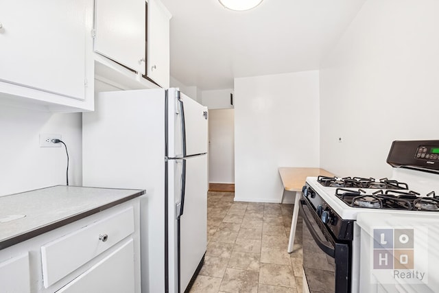 477 Fdr Dr Unit M1605, New York City, NY 10002 - kitchen featuring black gas stove, white cabinetry, freestanding refrigerator, stone finish floors, and baseboards
