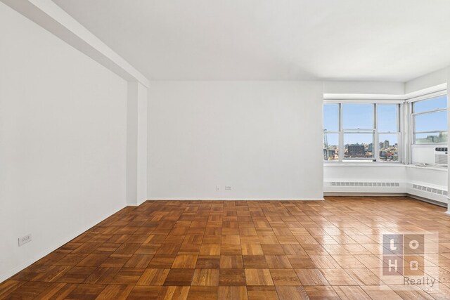 empty room featuring a view of city and radiator heating unit