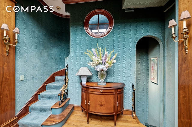 sitting room featuring stairway, wallpapered walls, baseboards, and wood finished floors