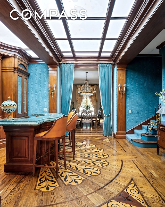 bar featuring stairs, parquet flooring, a notable chandelier, and a community bar
