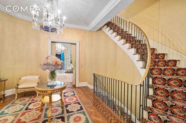 stairs featuring a notable chandelier, crown molding, baseboards, and parquet floors