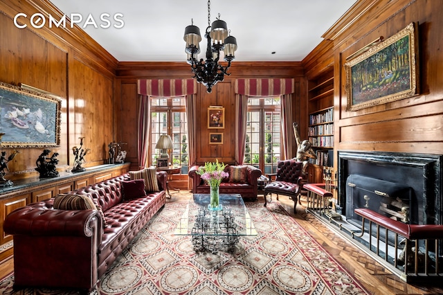 living area featuring wooden walls, a chandelier, ornamental molding, a fireplace, and wood finished floors