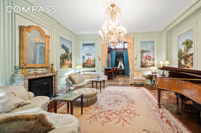 living area with crown molding, a decorative wall, a fireplace, and a chandelier