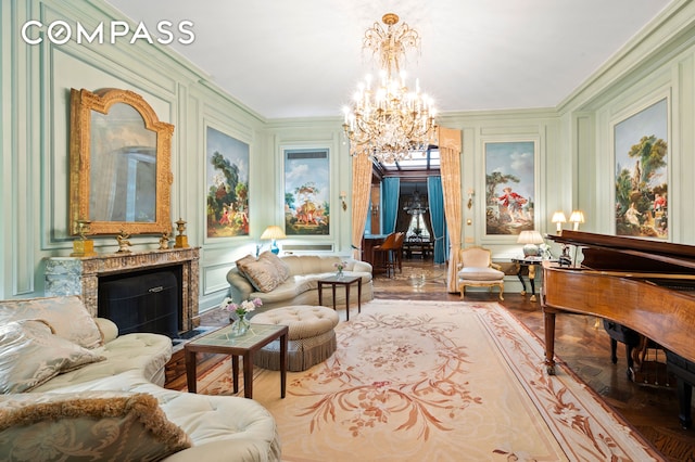 sitting room with a fireplace, wood finished floors, an inviting chandelier, ornamental molding, and a decorative wall