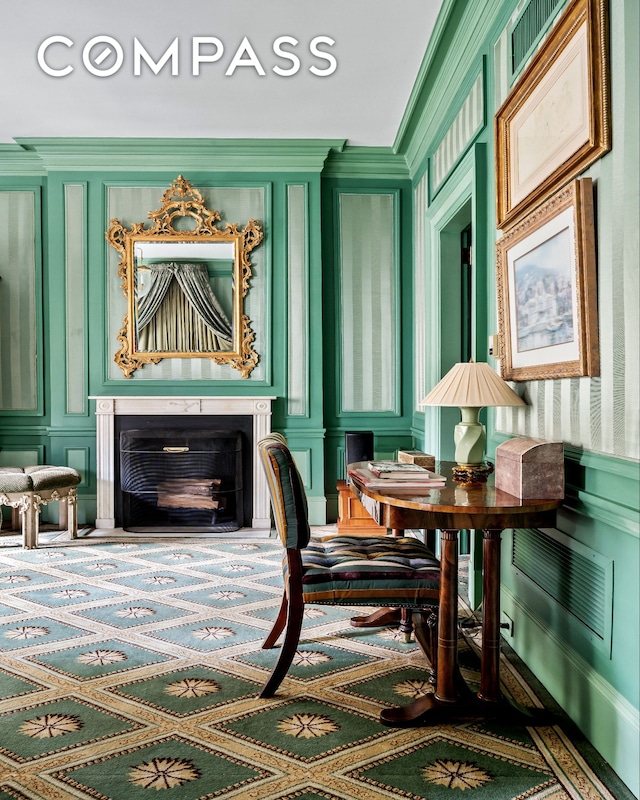 living area featuring wallpapered walls, a decorative wall, and ornamental molding