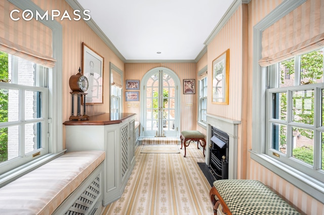 sitting room with a fireplace with flush hearth, ornamental molding, and french doors