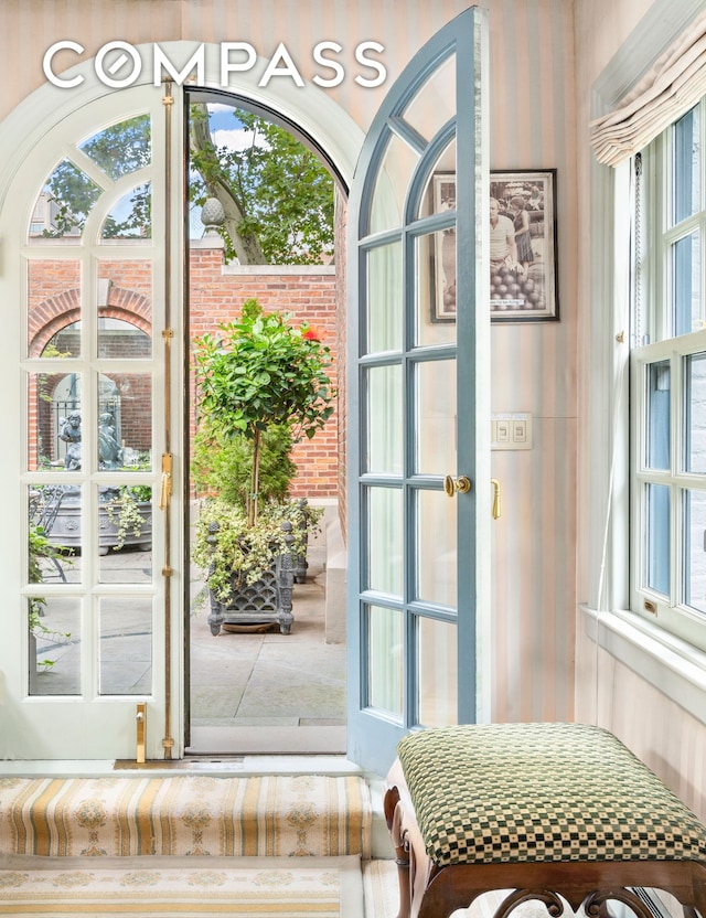 doorway to outside featuring wallpapered walls