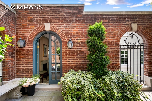 view of exterior entry featuring french doors and brick siding