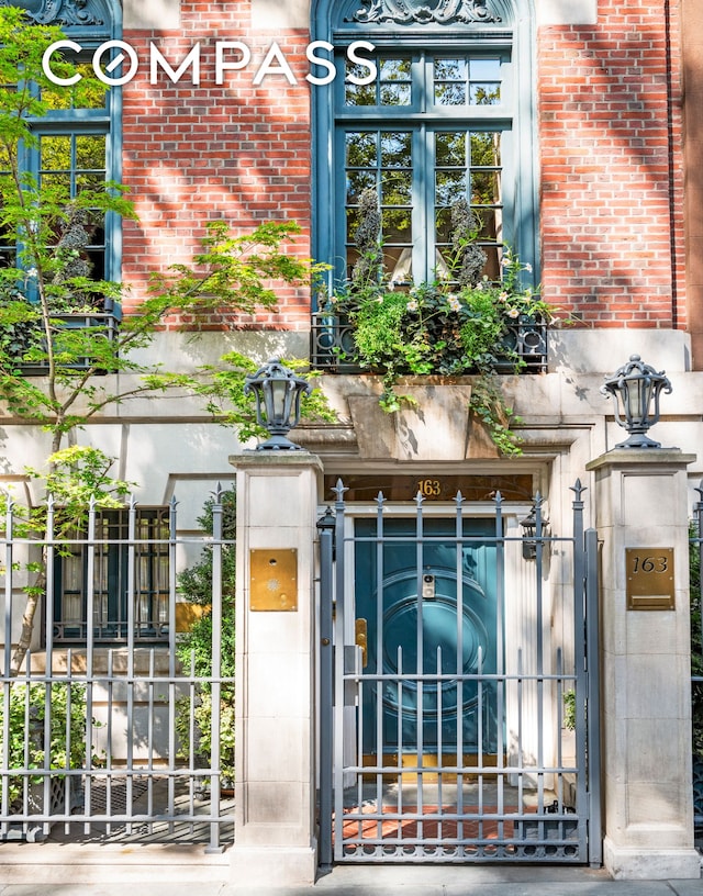 doorway to property with brick siding, fence, and a gate