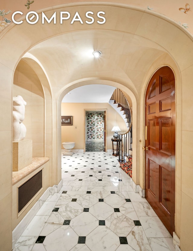 corridor featuring stairway, arched walkways, and marble finish floor