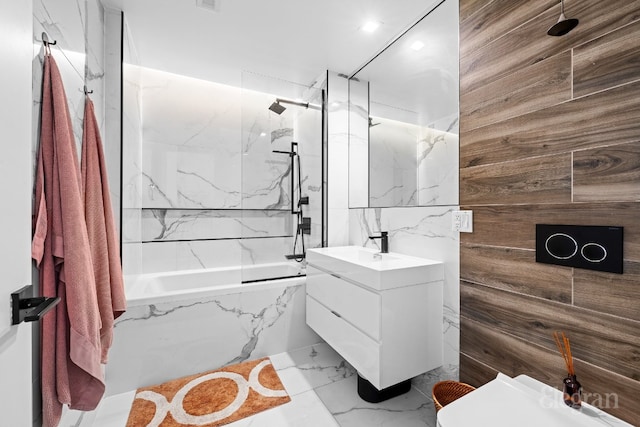 bathroom with a combined bath / shower with rainfall shower, wood walls, visible vents, vanity, and marble finish floor