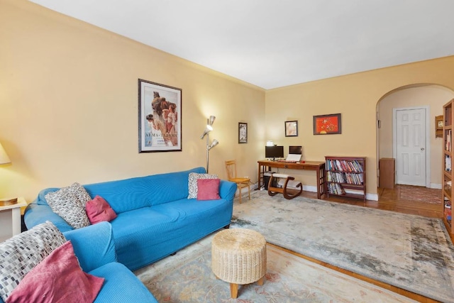 living room with arched walkways, baseboards, and wood finished floors