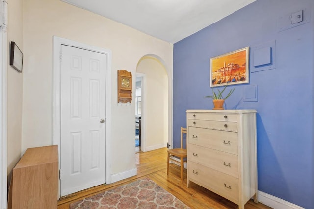 interior space featuring arched walkways, baseboards, and wood finished floors