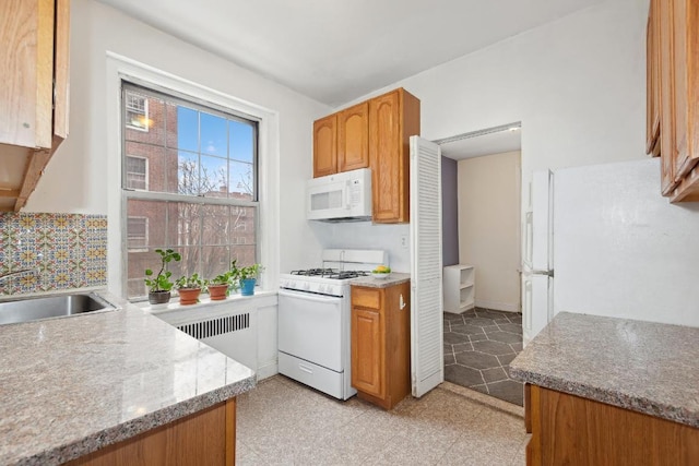 kitchen with brown cabinets, white appliances, a sink, and radiator