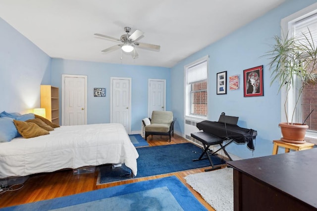 bedroom with ceiling fan, baseboards, multiple closets, and wood finished floors