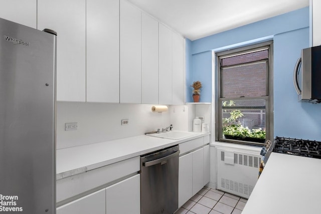 420 E 55th St Unit 11M, New York City, NY 10022 - kitchen featuring appliances with stainless steel finishes, radiator, healthy amount of natural light, and white cabinetry
