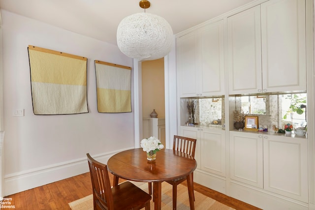 dining area with light wood finished floors and a chandelier