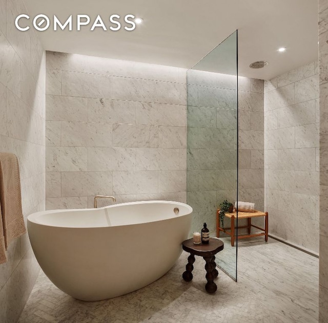 full bathroom featuring a freestanding tub and tile walls