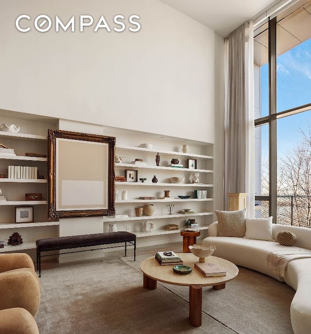 living room with built in shelves, carpet, and a towering ceiling