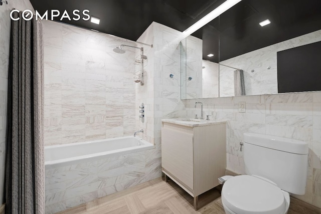 bathroom featuring tiled shower / bath combo, tile walls, toilet, and vanity