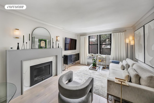 living room with ornamental molding, a high end fireplace, visible vents, and light wood-style flooring