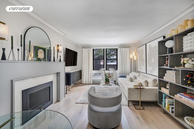 living room with ornamental molding, visible vents, light wood finished floors, and a premium fireplace