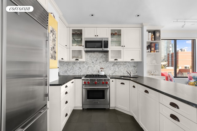 kitchen featuring glass insert cabinets, dark countertops, white cabinetry, and high end appliances