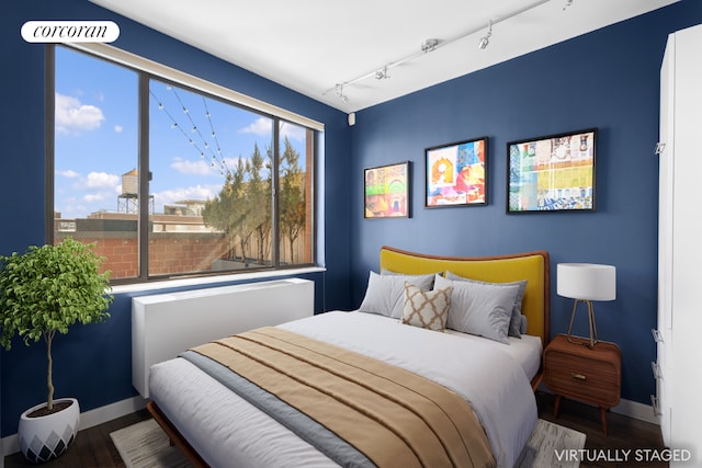 bedroom featuring rail lighting, baseboards, and wood finished floors