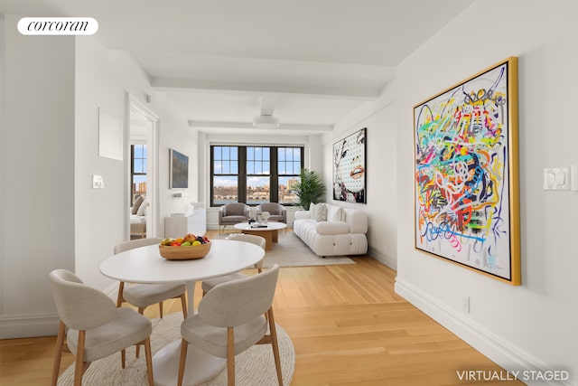 dining room with baseboards, visible vents, beamed ceiling, and light wood finished floors