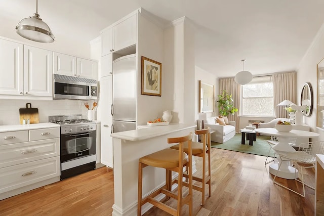 kitchen with appliances with stainless steel finishes, light wood-type flooring, white cabinets, and light countertops