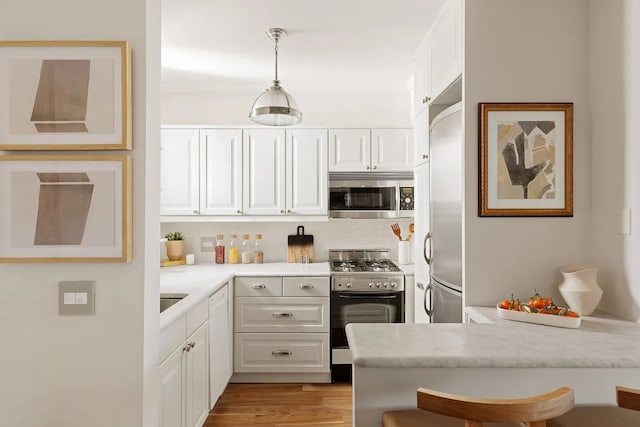 kitchen with white cabinetry, appliances with stainless steel finishes, pendant lighting, and a breakfast bar area