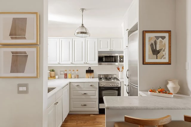 kitchen with tasteful backsplash, appliances with stainless steel finishes, light wood-style floors, white cabinetry, and a peninsula