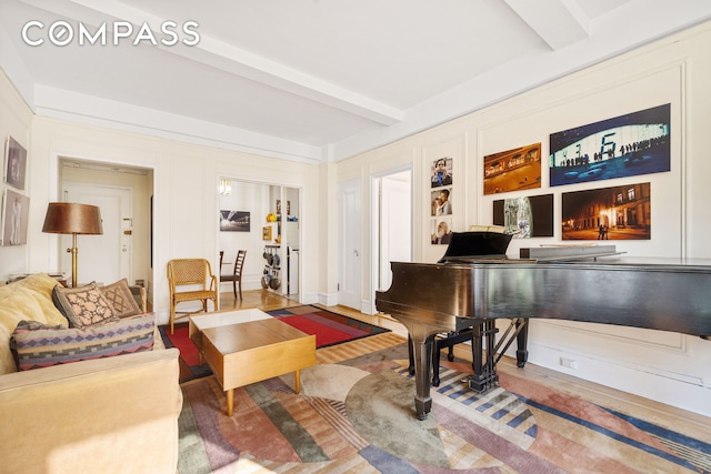 living area featuring built in features, beamed ceiling, and wood finished floors