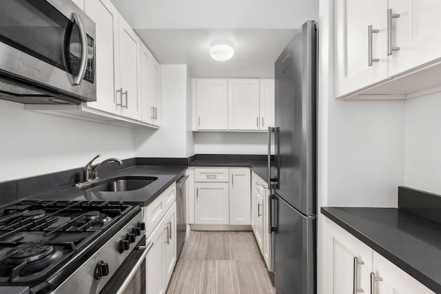 kitchen featuring stainless steel appliances, dark countertops, and white cabinetry