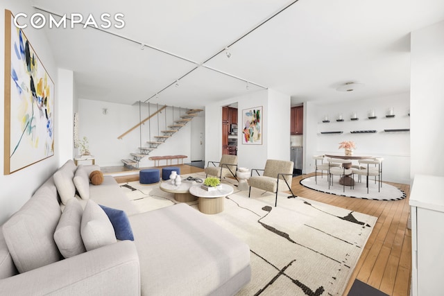 living area featuring stairway, rail lighting, and light wood-type flooring