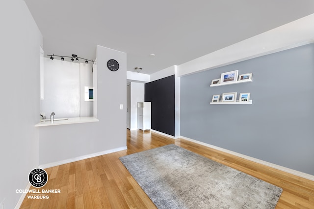 empty room featuring a barn door, wood finished floors, and baseboards