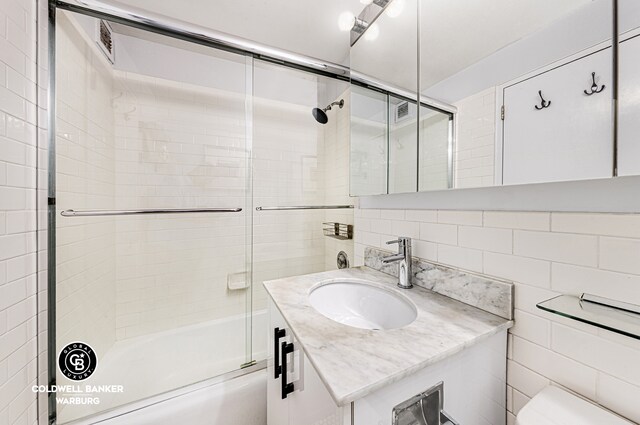 7 E 14th St Unit 1625, New York City, NY 10003 - full bathroom with tile walls, vanity, bath / shower combo with glass door, and toilet