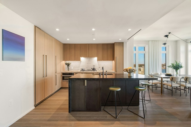 543 W 122nd St Unit 18A, New York City, NY 10027 - kitchen with a sink, dark countertops, wood finished floors, decorative backsplash, and recessed lighting