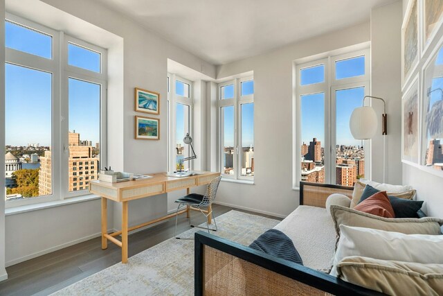 bedroom with a view of city, baseboards, and wood finished floors