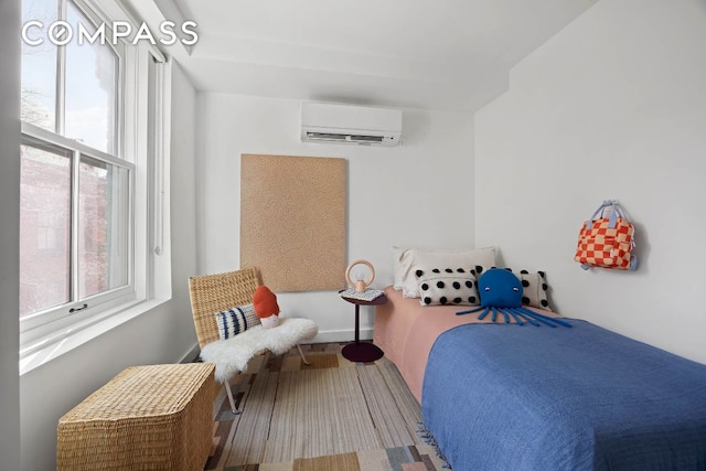 bedroom with wood finished floors, baseboards, and a wall mounted AC