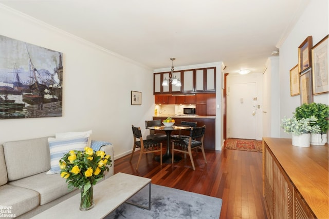 living area with an inviting chandelier, ornamental molding, and dark wood-type flooring