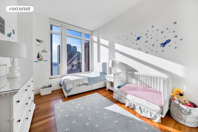 bedroom with wood finished floors and a city view