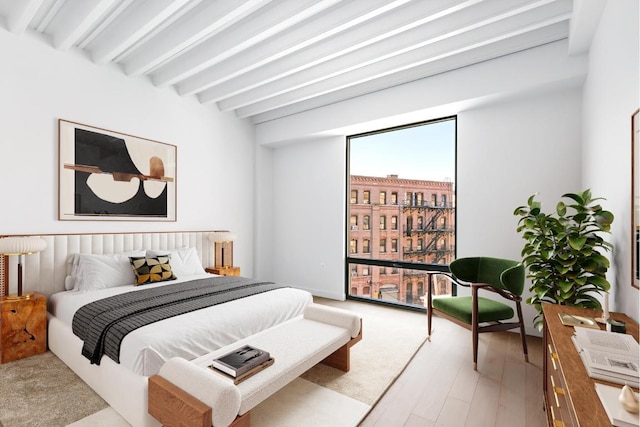 bedroom featuring beam ceiling and light wood-style floors